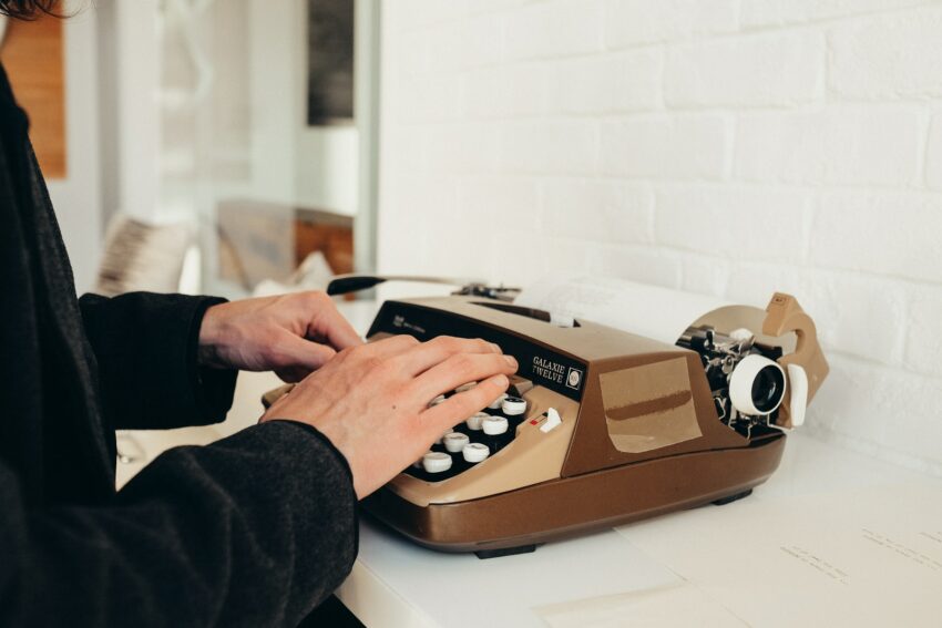 person in black long sleeve shirt using brown and white rotary phone